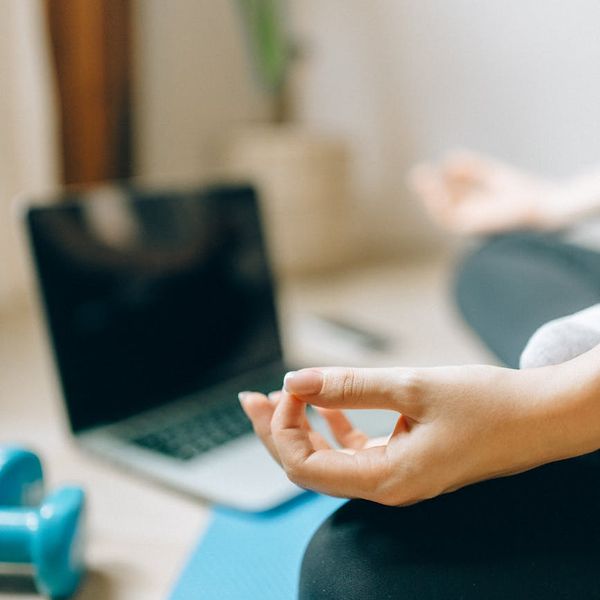 A person rolling out a yoga mat in a bright room.