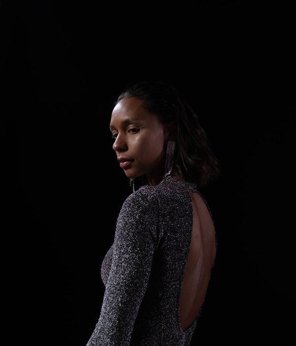 Woman in a calm yoga pose in a dark studio with mint light.